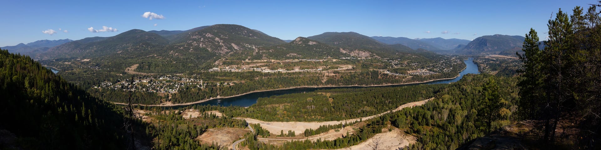 A mountainous landscape with a river, forested areas, and a small town.