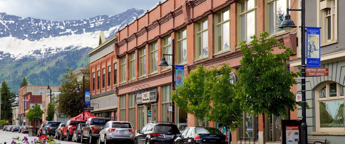 A street lined with parked cars, a Heritage Library, and a Post Office.