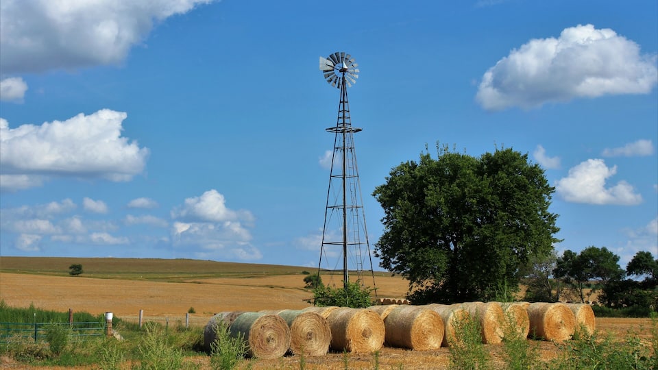 A windmill, hay bales, and a clear blue sky.