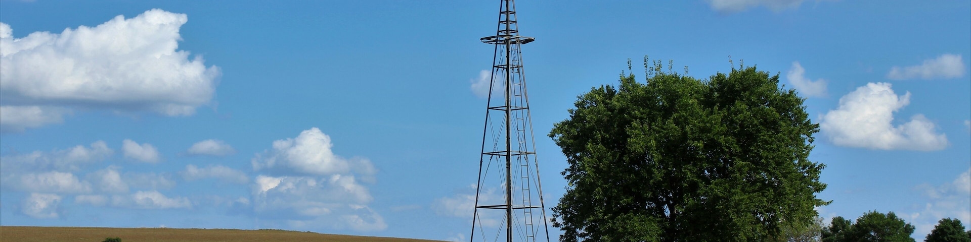 Kansas farm Windmill with hay bales, tree's, blue sky and clouds that's south of Lucas Kansas USA out in the country.