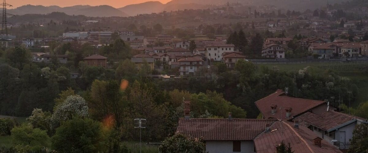 A sunset over a town with mountains in the background.