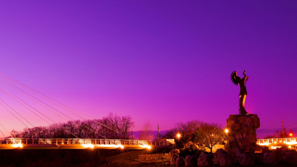 A bridge with a statue in the center, set against a purple sky.