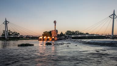 A river with a bridge and a monument with flames.