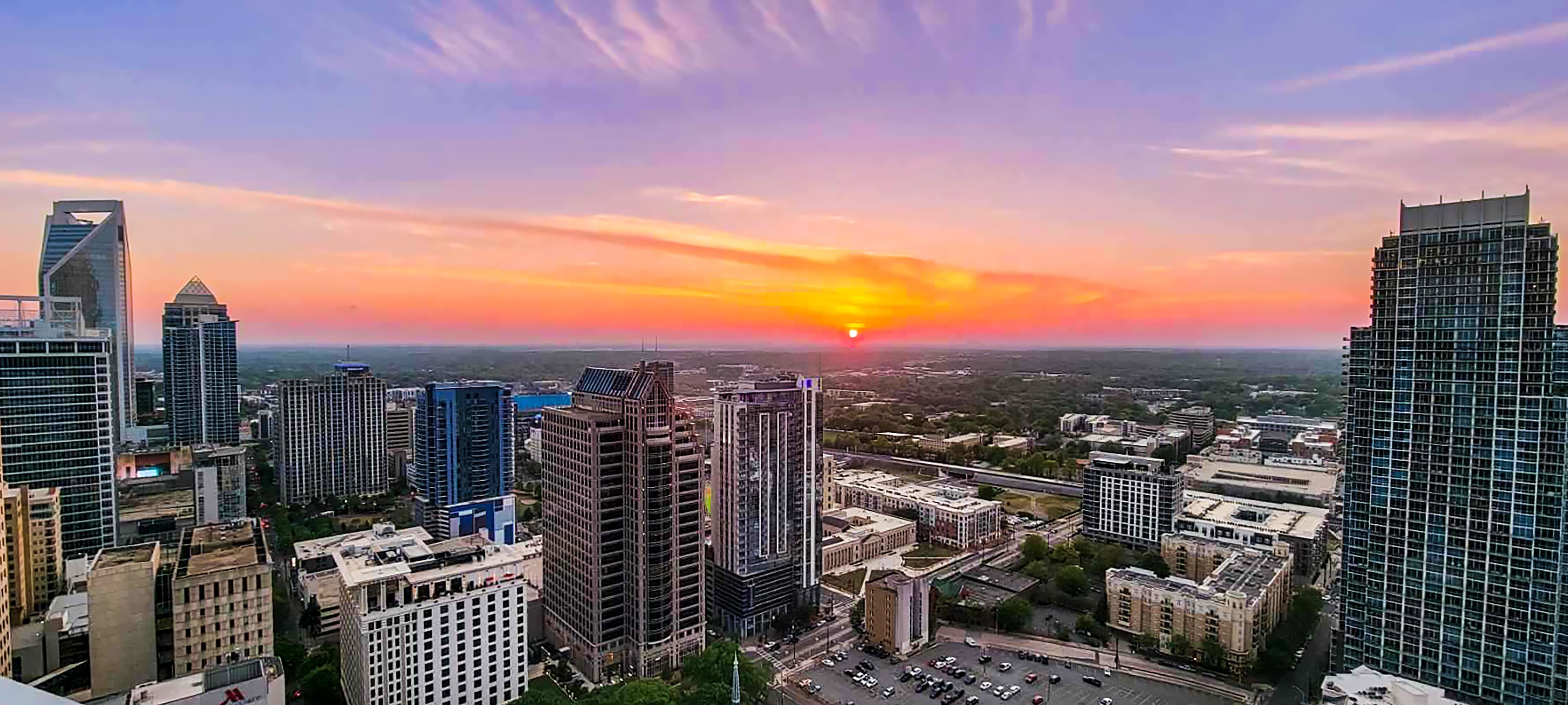 A cityscape at sunset with modern skyscrapers and a clear sky.