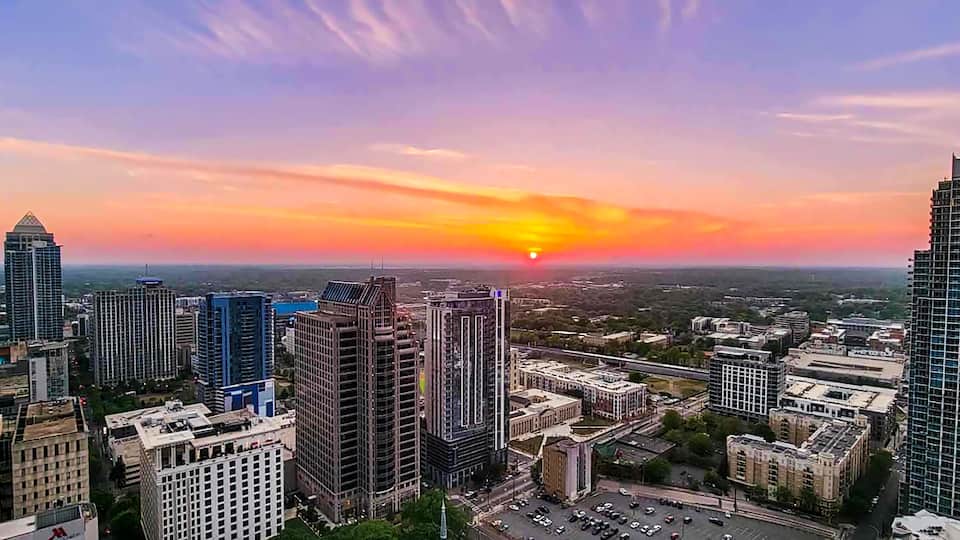 A cityscape at sunset with modern skyscrapers and a clear sky.