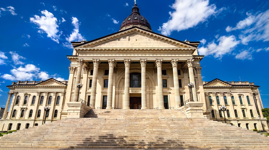 Kansas State Capitol in Topeka. Historic French Renaissance Revival architecture features a limestone facade with columns and a grand staircase under a blue sky