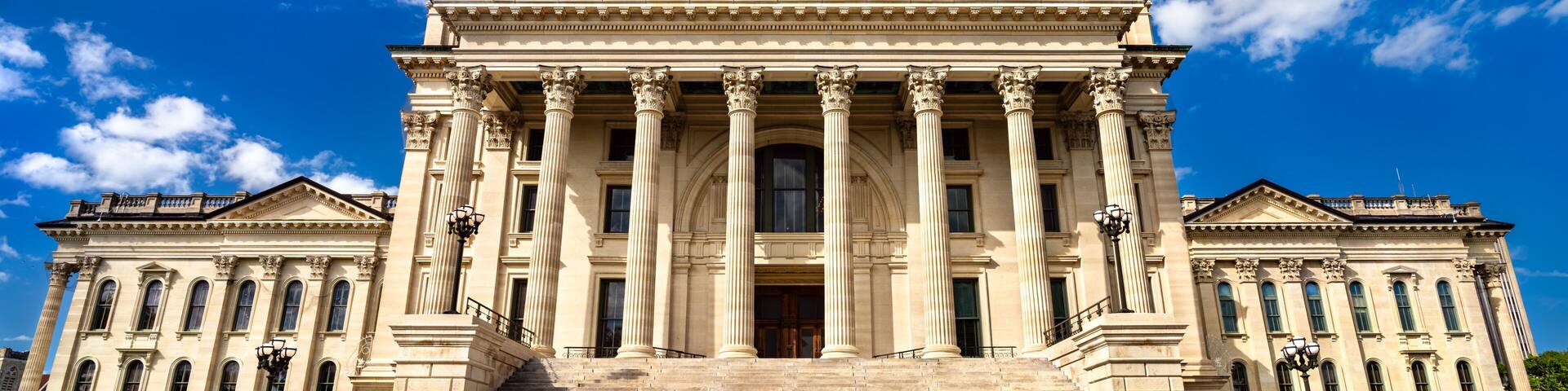 Kansas State Capitol in Topeka. Historic French Renaissance Revival architecture features a limestone facade with columns and a grand staircase under a blue sky