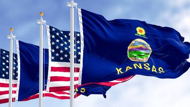 Kansas state flag and American flag waving in the wind on a clear day