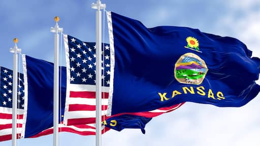 Kansas state flag and American flag waving in the wind on a clear day
