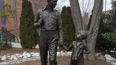 Estatua de un hombre y un niño tomados de la mano, con una placa debajo.