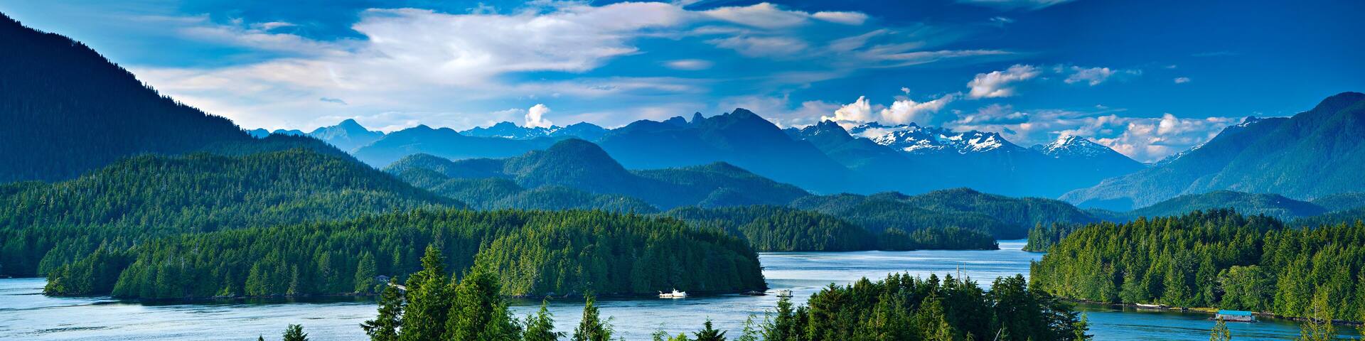 A mountainous landscape with a lake, forested areas, and snow-capped peaks.