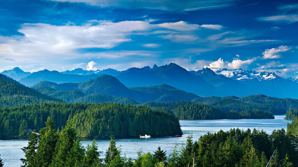 A mountainous landscape with a lake, forested areas, and snow-capped peaks.