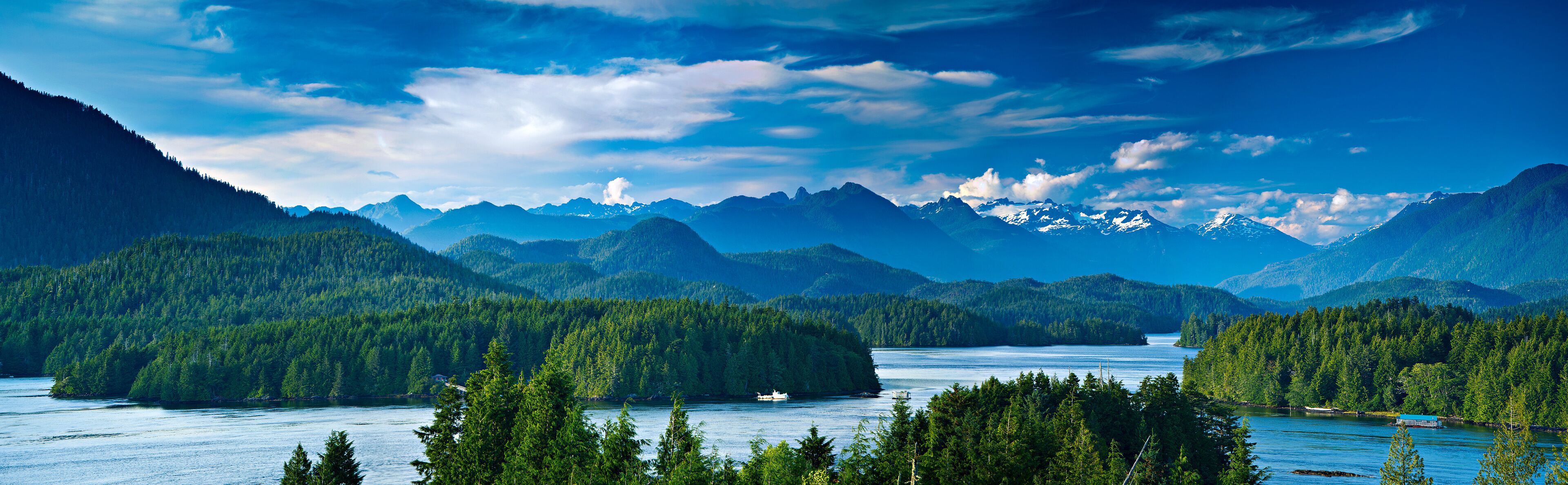 A mountainous landscape with a lake, forested areas, and snow-capped peaks.