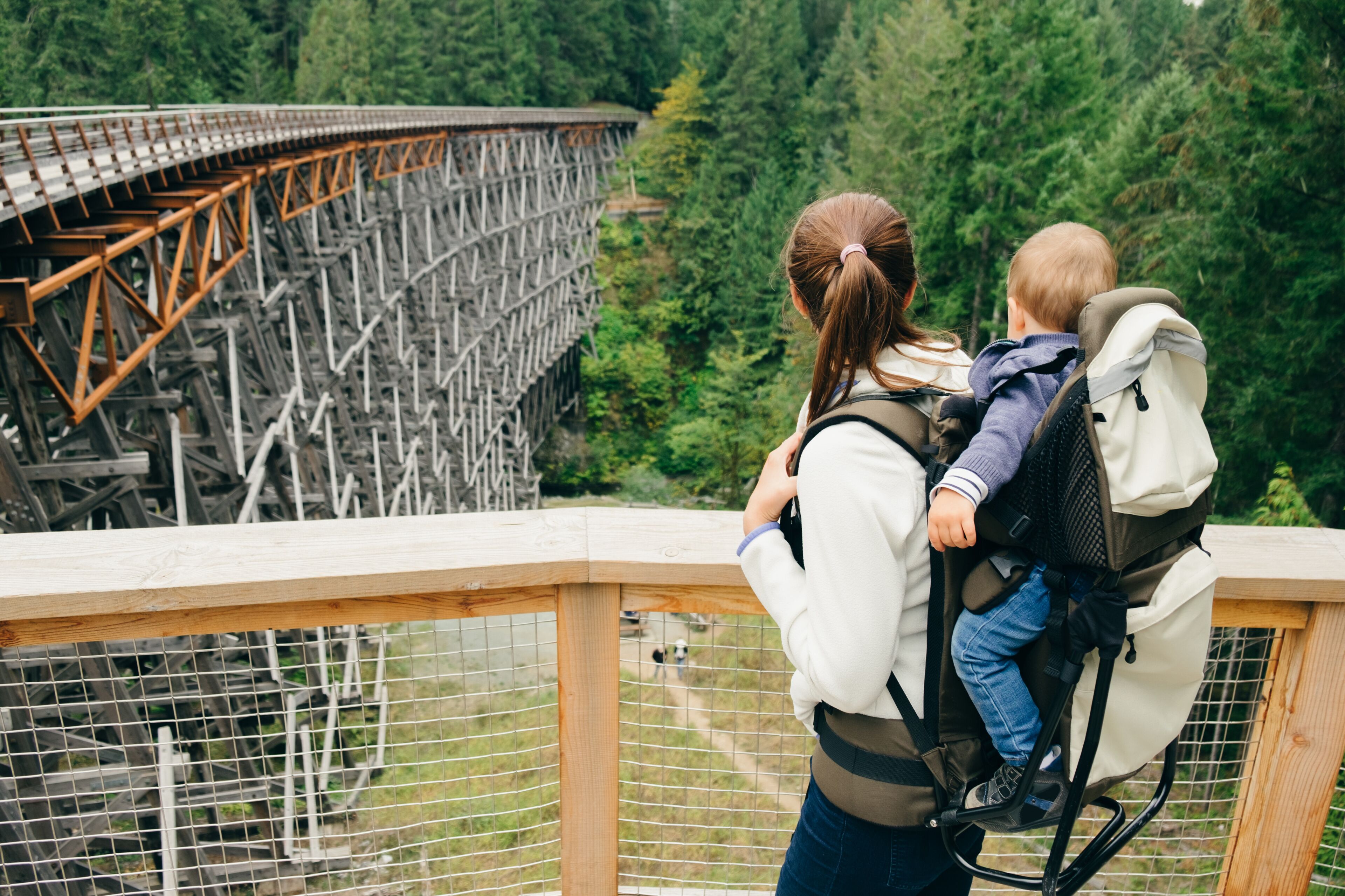 Young woman carrying son on back, rear view, Kinsol Trestle Bridge, British Columbia, Canada