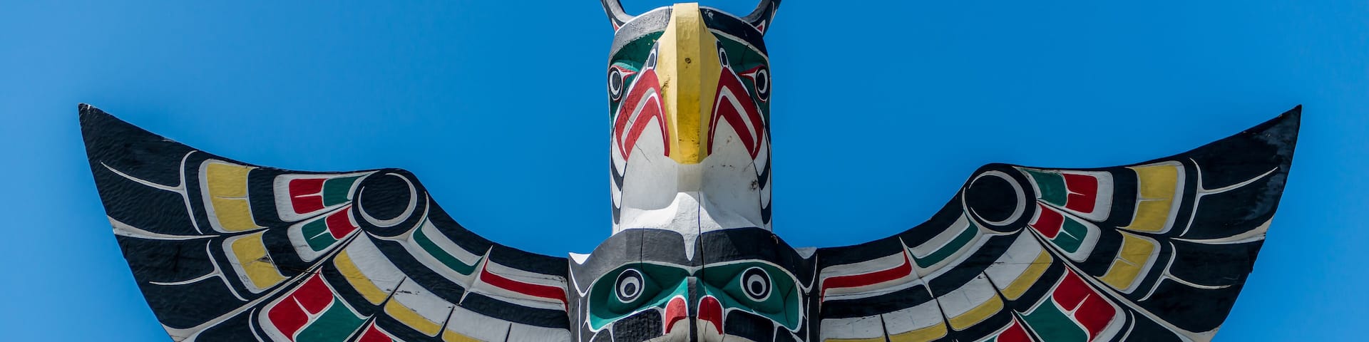 A totem pole with intricate designs and a bird-like figure.
