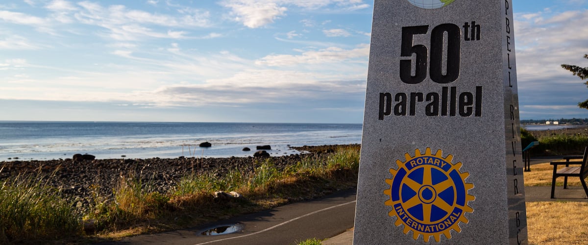 Un monument en granit portant l’inscription « 50e parallèle » et le logo du Rotary International.