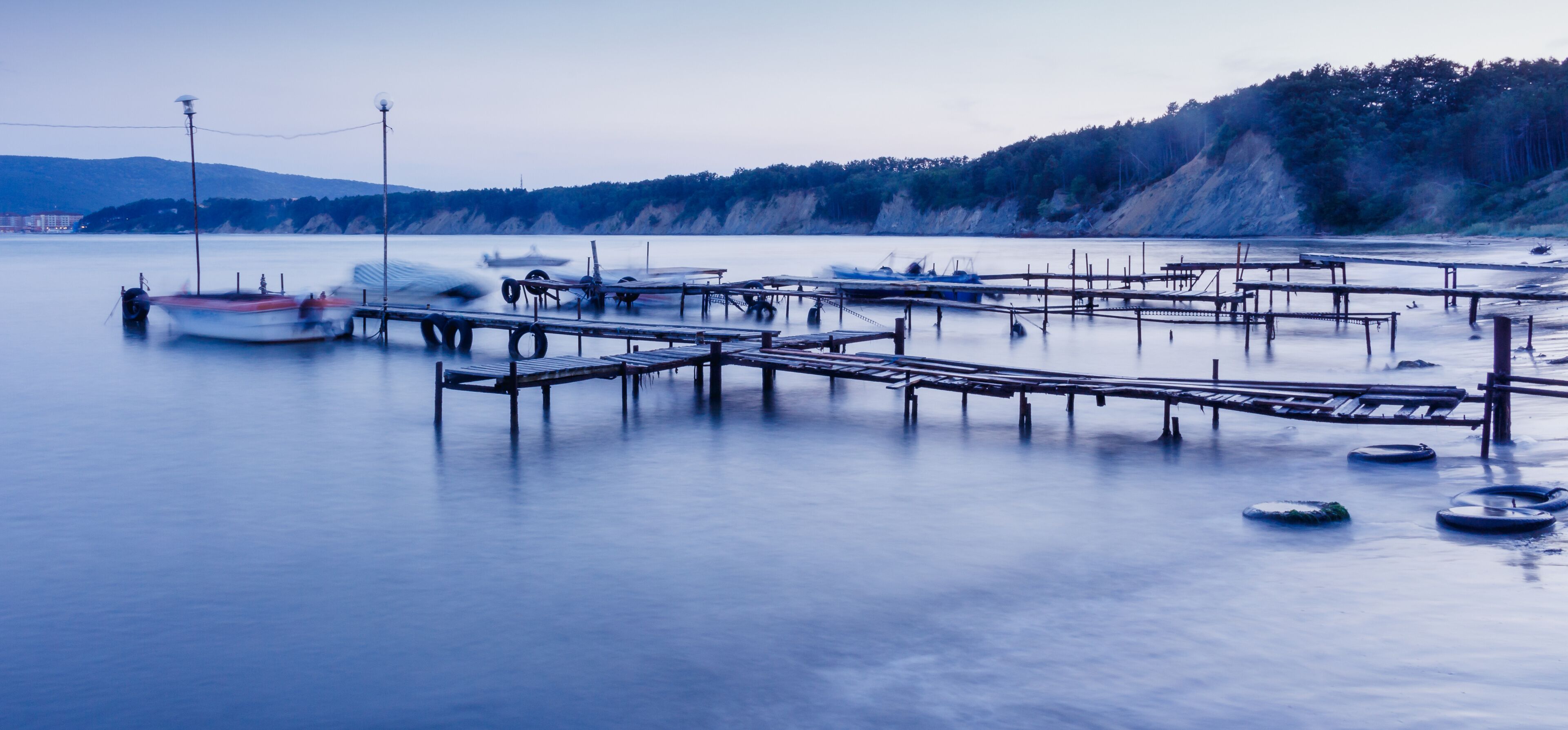 Fishing boats and the pier. Long exposure seascape during sunset, blue hour in the harbour near Byala, Bulgaria.