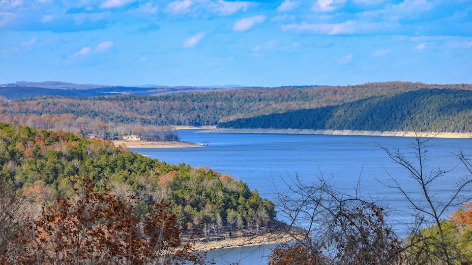 A lake surrounded by forested hills, a small dock, and a clear sky.