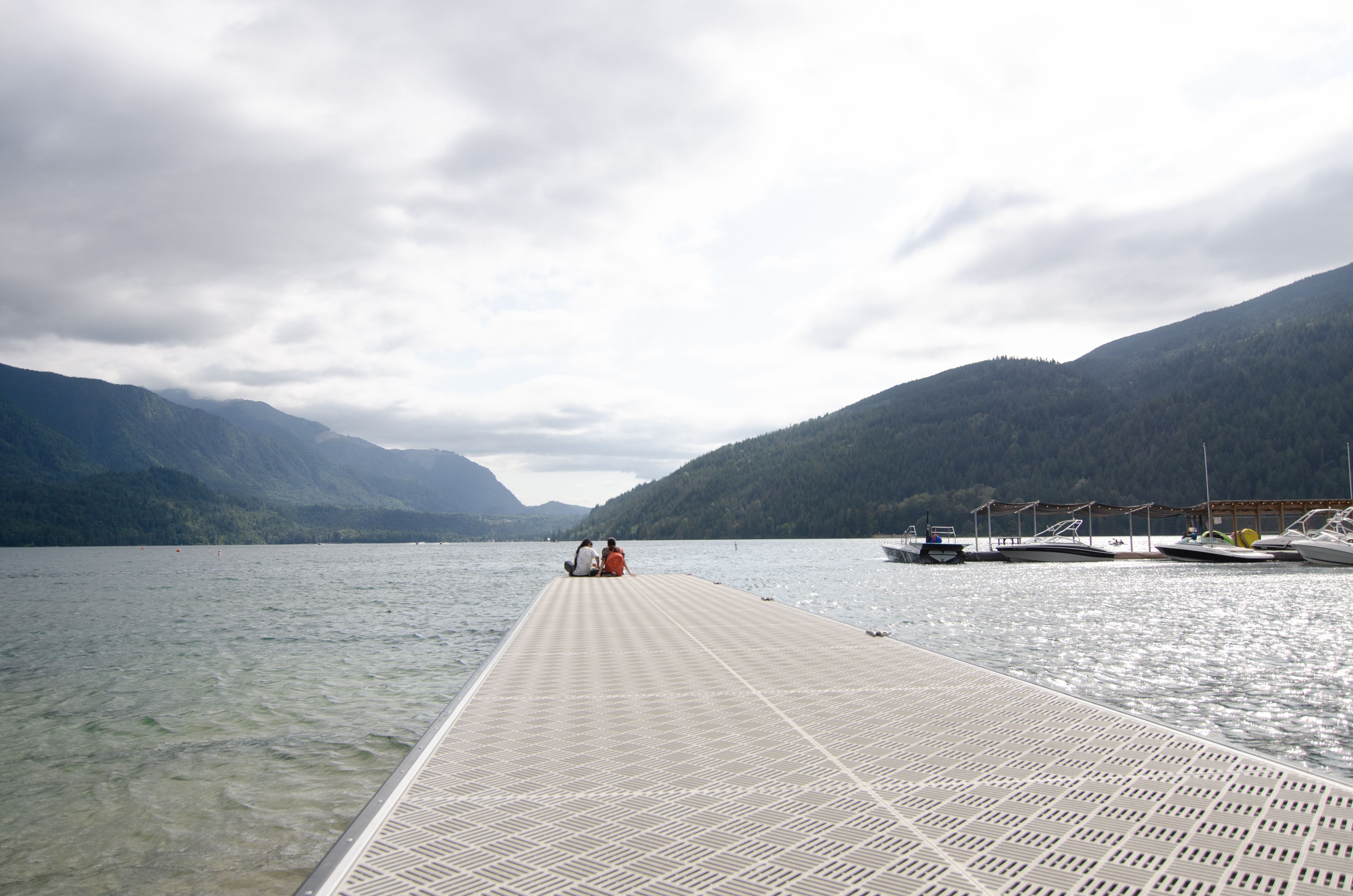 A pier extending into a calm lake with mountains in the background.