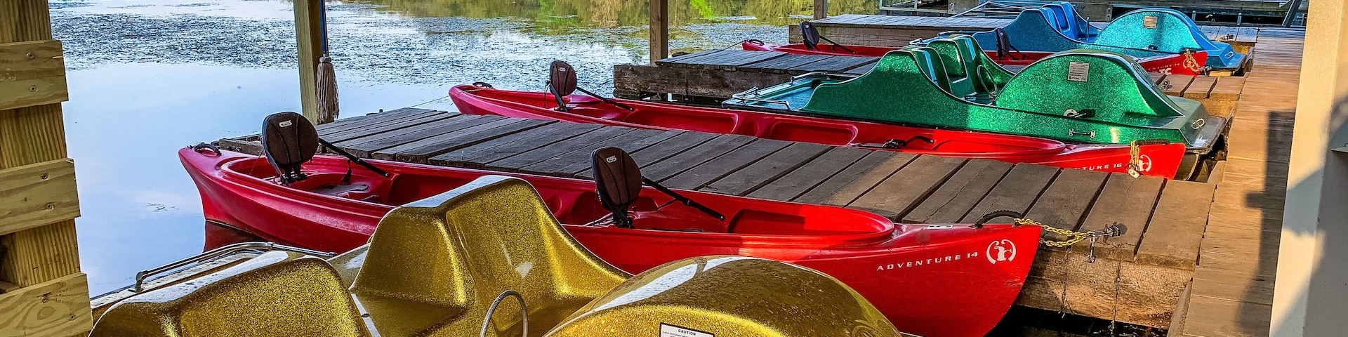 Um cais coberto com caiaques e um barco a pedal.