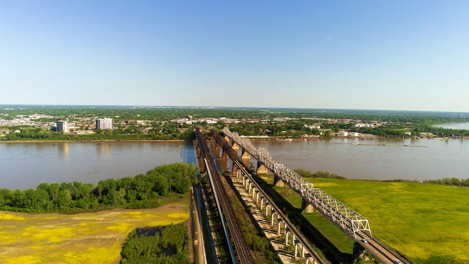 A long bridge spanning a river with a cityscape in the background.