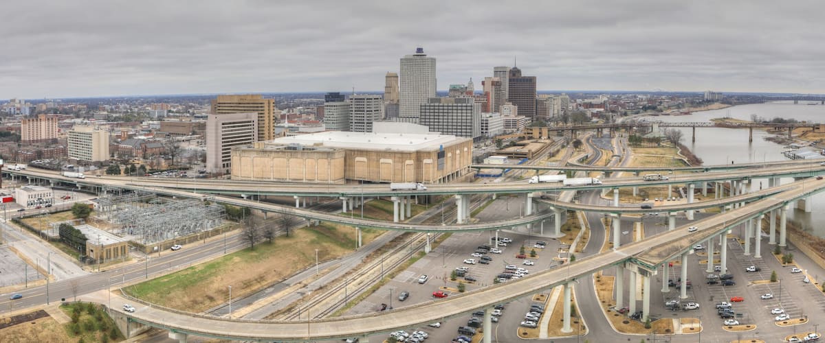 A complex highway interchange with multiple overpasses and a river in the background.