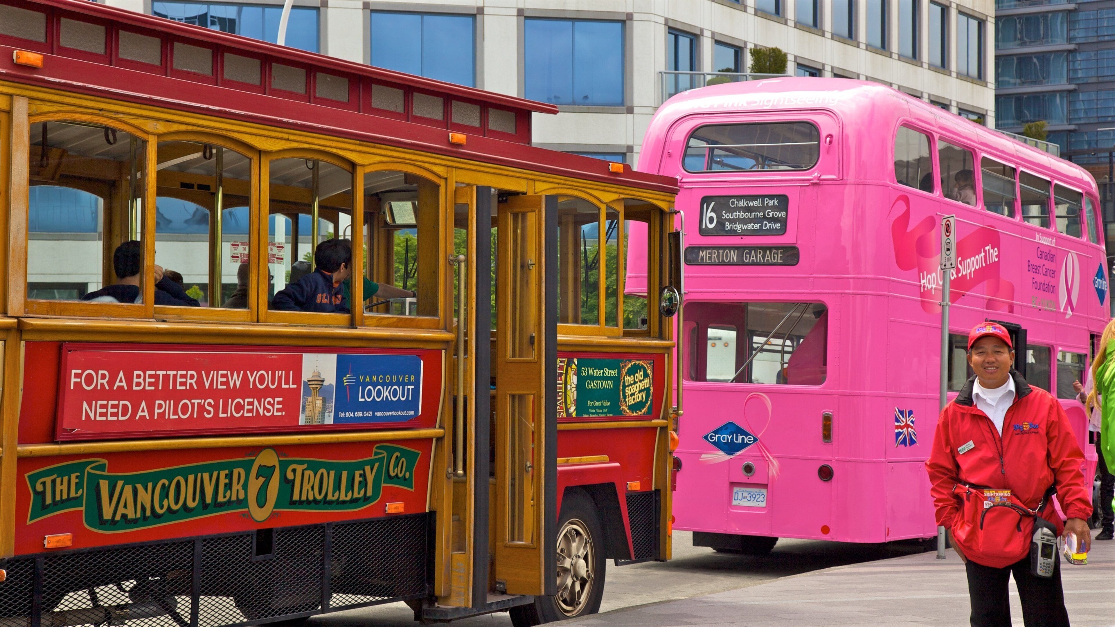 Ein rosafarbener Doppeldeckerbus und ein gelber Straßenbahnwagen.