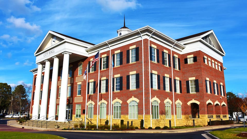 A red brick building with white columns and a clock tower, labeled "City Hall."