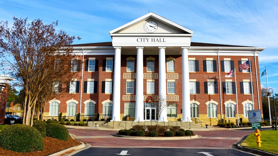 A brick building with a clock and columns labeled "City Hall".