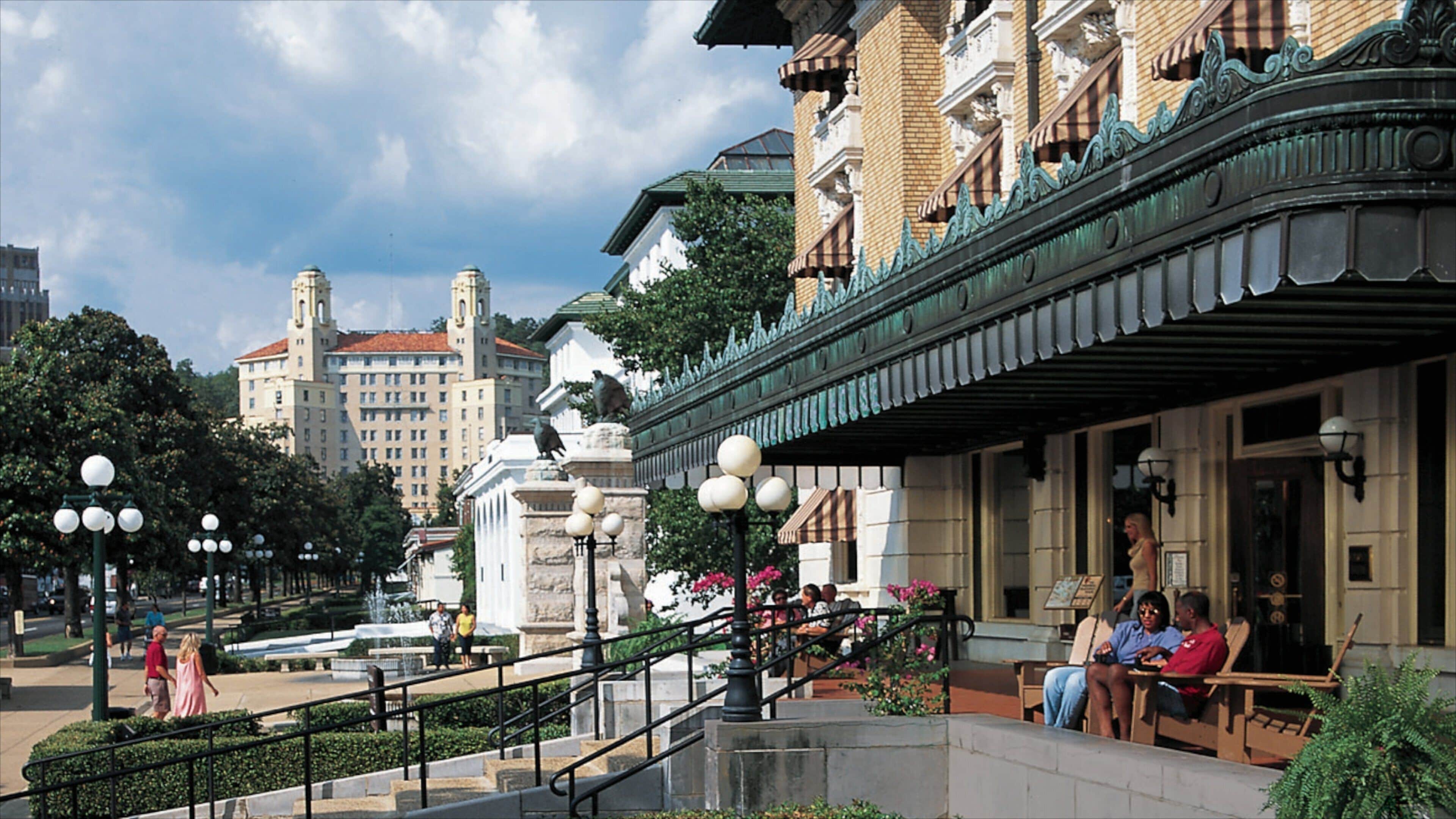 A historic building with ornate architecture, a fountain, and people sitting on benches.