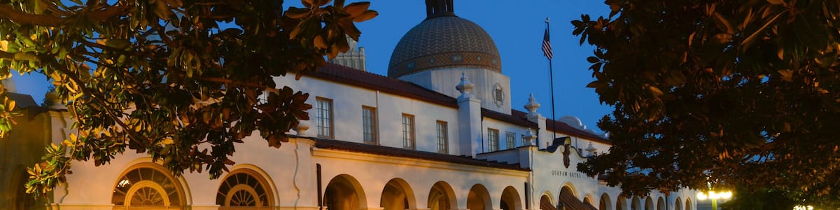 A historic building with a dome and arched windows at dusk.
