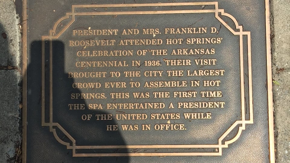 A historical plaque on a brick sidewalk.