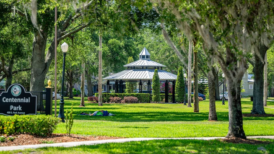 Centennial Park with a gazebo, trees, and a sign.