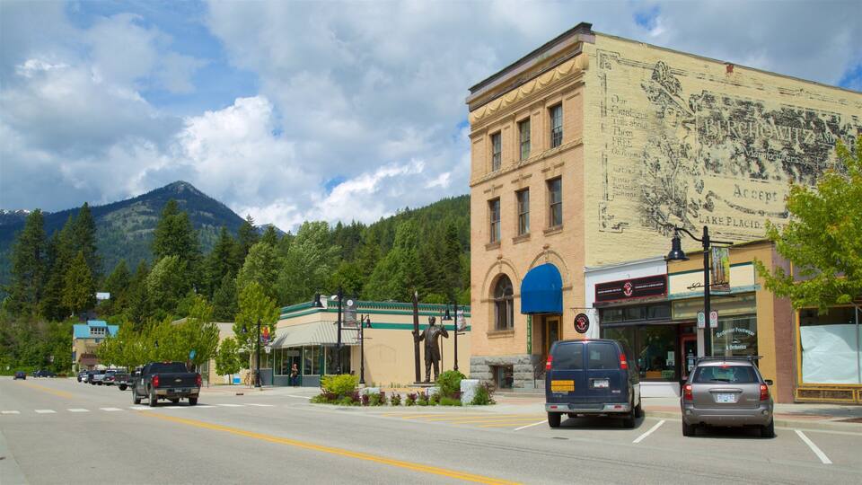 A street with cars, a building with a mural, and mountains in the background.