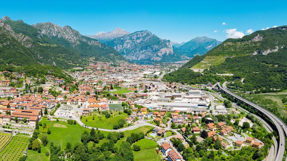 A town nestled between mountains with a river and a highway.