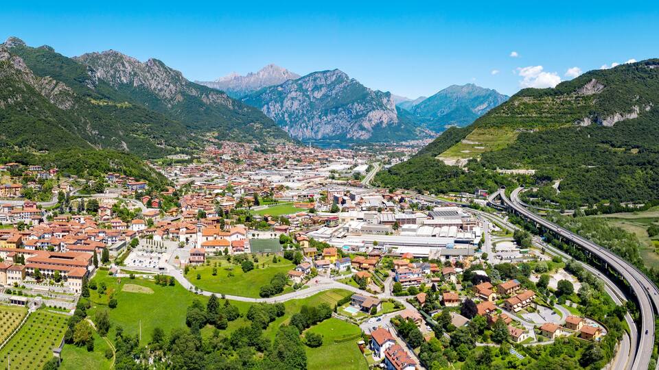 A town nestled between mountains, with a river and a highway.