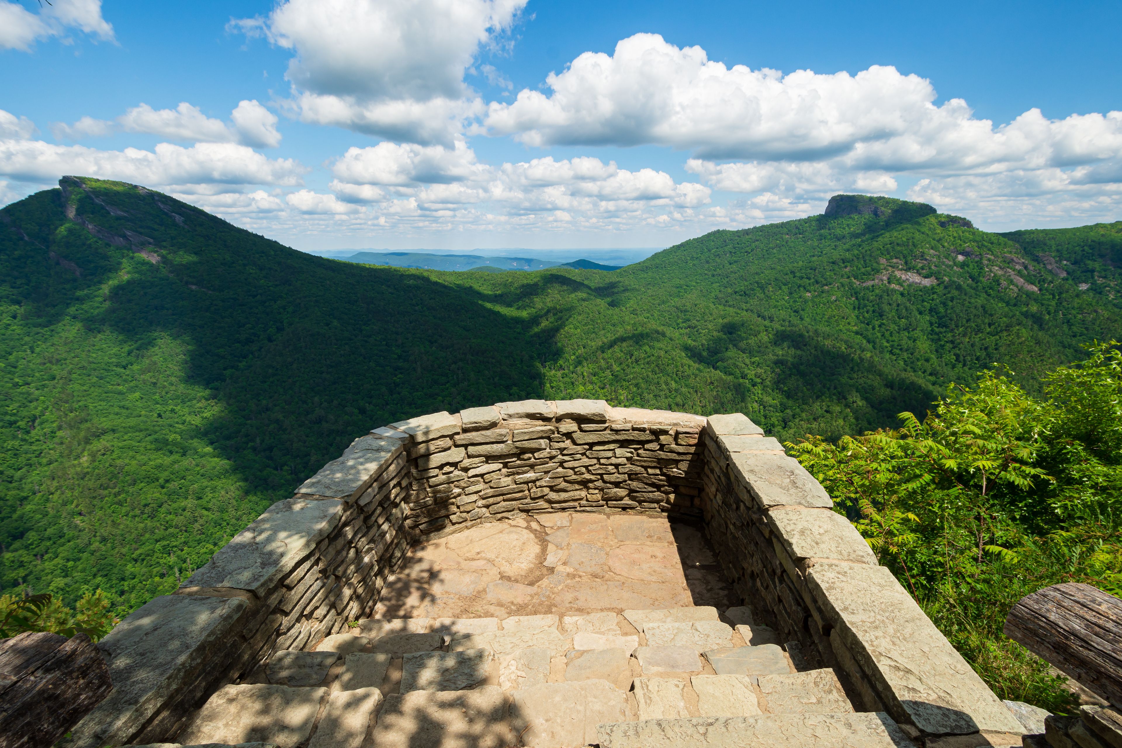 A stone staircase leading up to a stone wall overlooking a mountainous landscape.