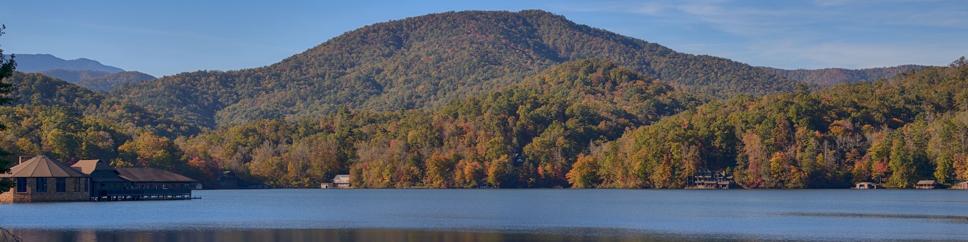 A calm lake with a mountain in the background and a lodge on the left.
