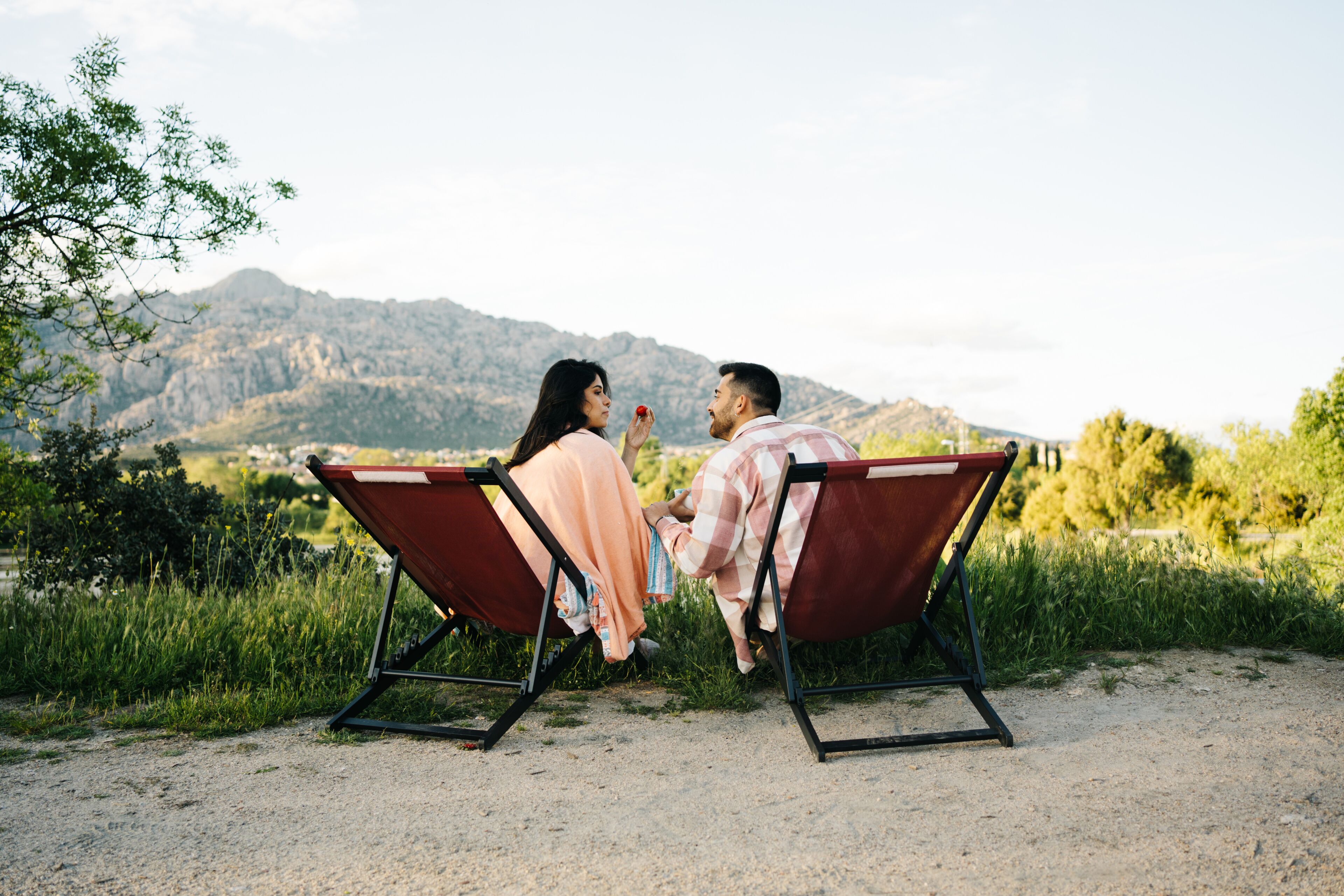 Traveling couple sitting in camping chairs in mountainous terrain