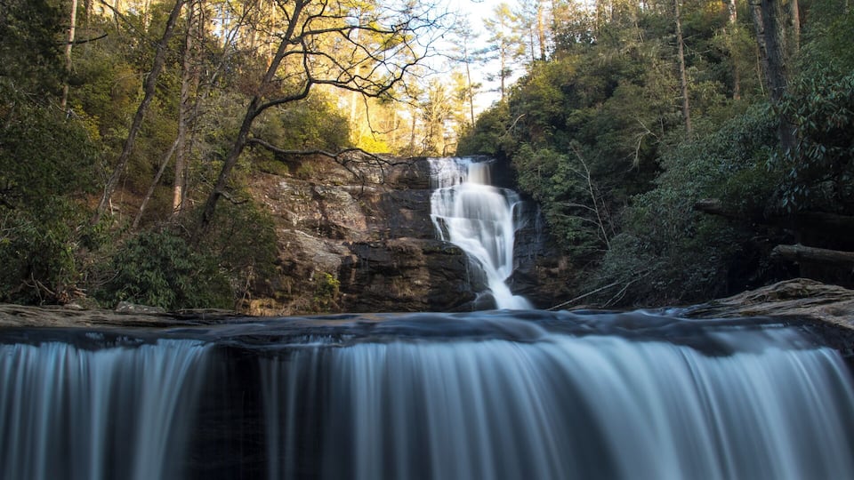 A waterfall cascading over a rocky cliff surrounded by dense forest.