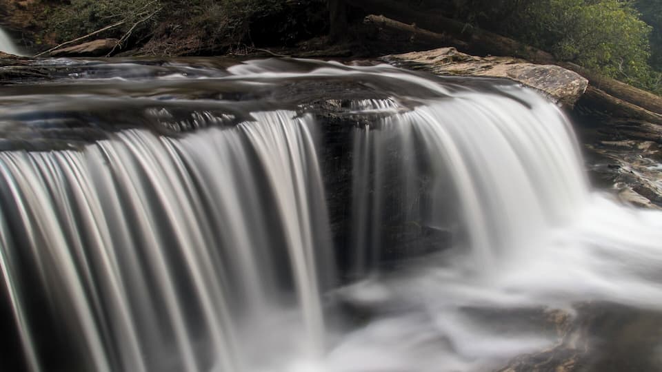 A waterfall cascading over rocks in a forested area.