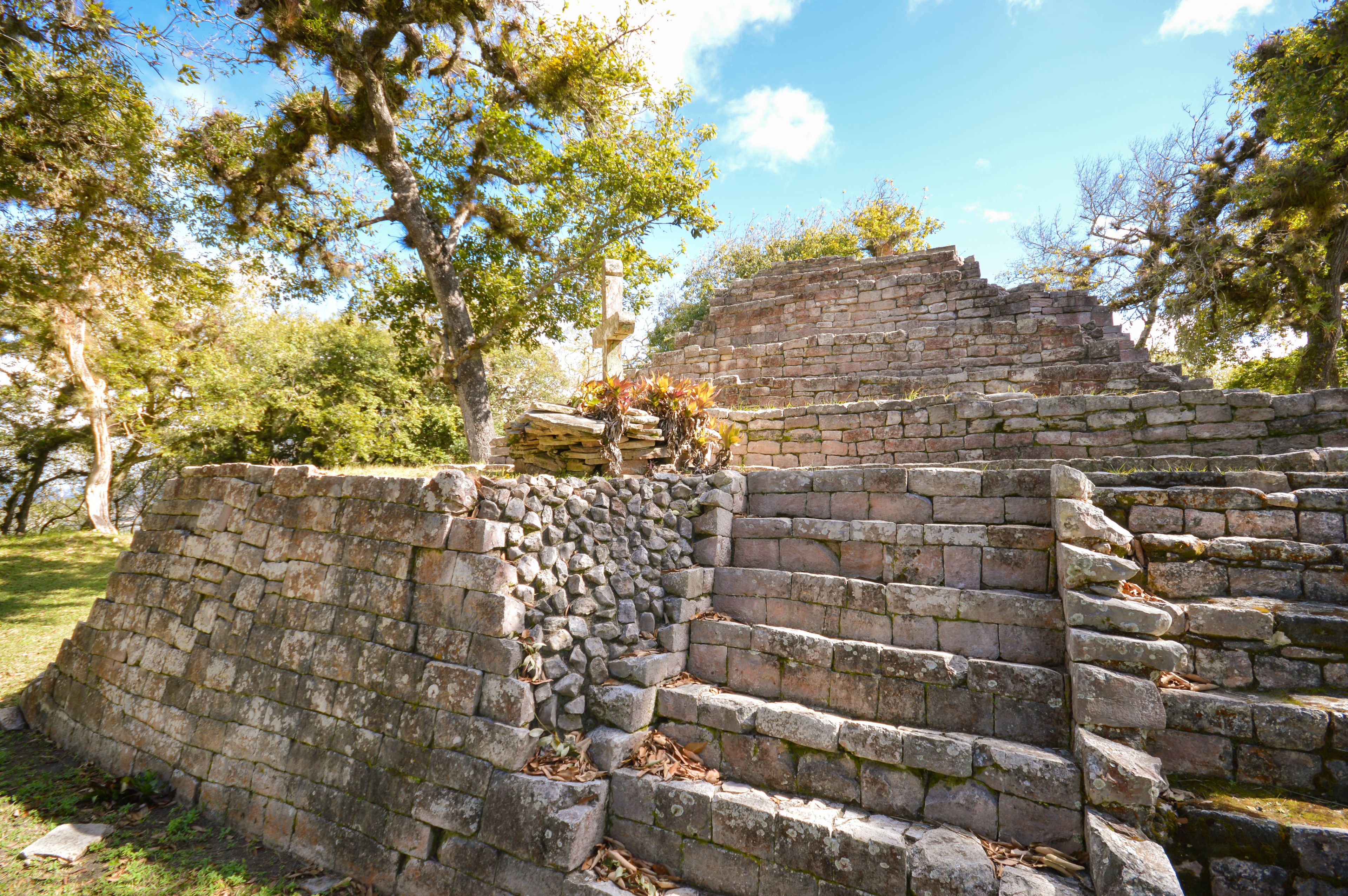 Ancient stone steps leading up to a pyramid-like structure surrounded by trees.