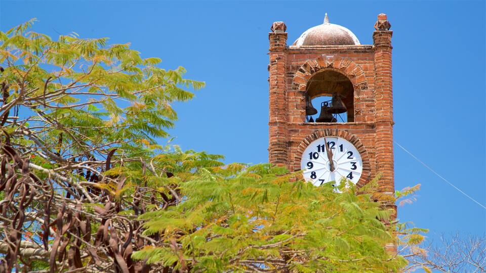 A clock tower with a dome and bells, surrounded by trees.