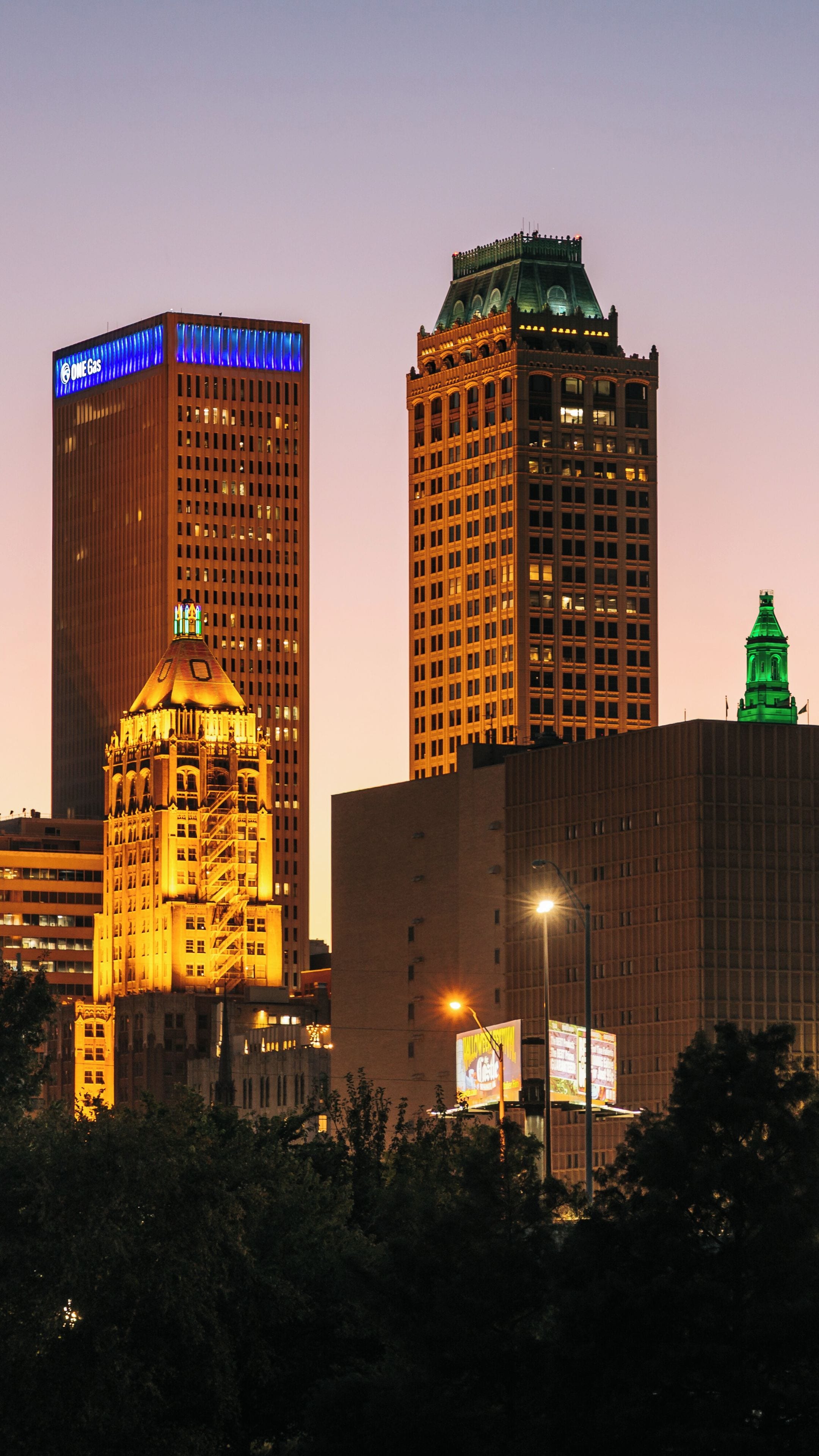 Silhueta urbana com edifícios iluminados ao entardecer.