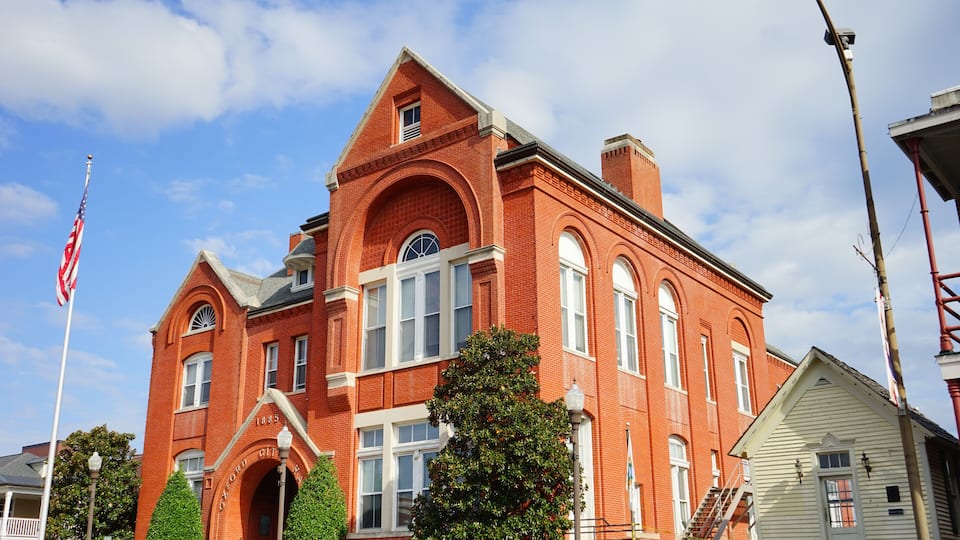 A red brick building with arched windows and a flagpole.