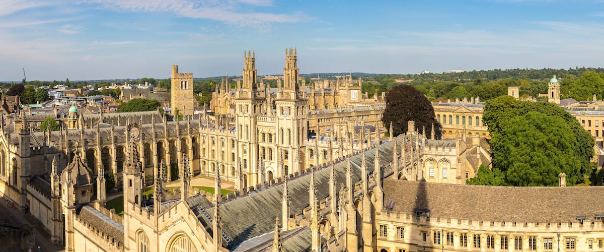 A historic cathedral with intricate Gothic architecture, surrounded by lush greenery and other historic buildings.