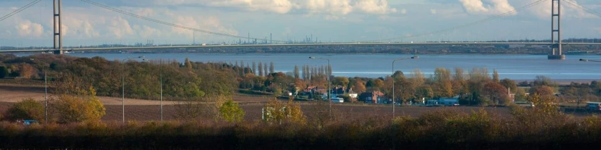 A bridge over a river, with fields and trees in the foreground.