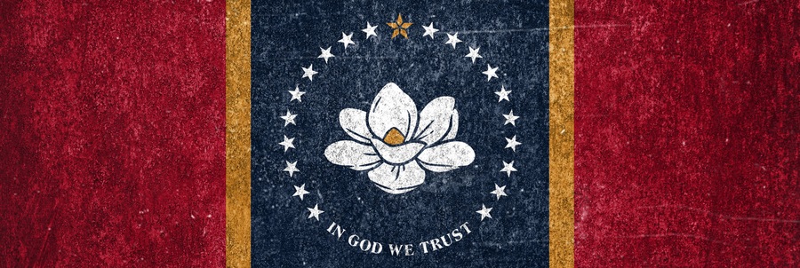 A flag with a white flower emblem, stars, and the phrase 'IN GOD WE TRUST' on a red background.