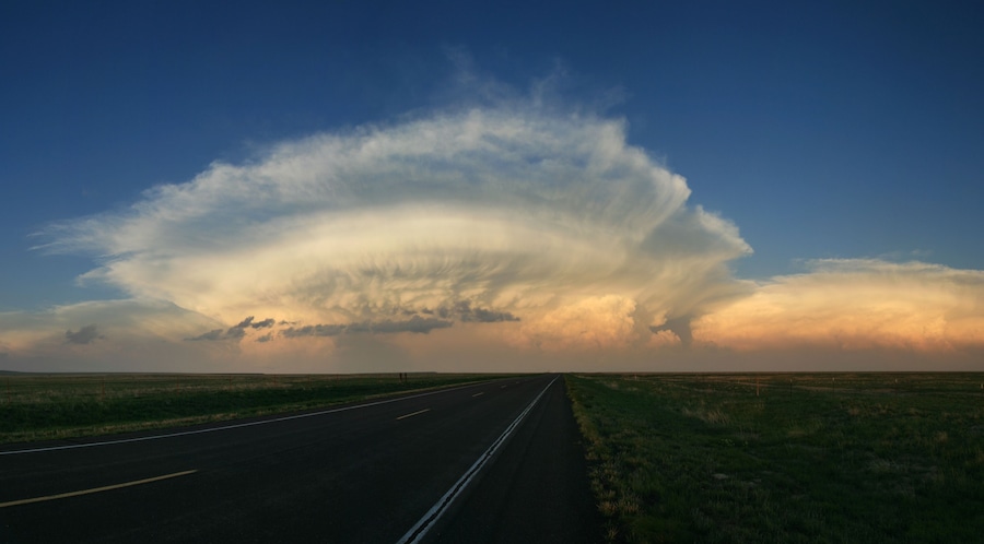 Carretera que se extiende hasta el horizonte bajo un cielo impresionante con una gran formación de nubes.