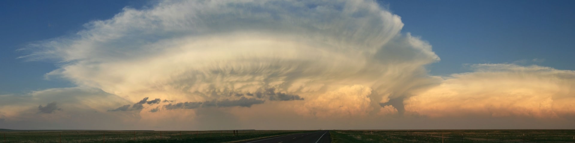 Carretera que se extiende hasta el horizonte bajo un cielo impresionante con una gran formación de nubes.